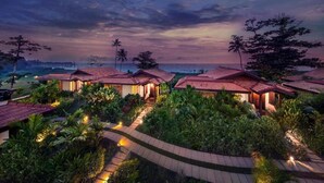 A resort with multiple bungalow-style accommodations, surrounded by lush greenery and a view of the ocean. - Niraamaya Retreats Backwaters and Beyond, Kumarakom (Kottayam)