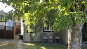 Un chemin bordé d’arbres mène à une maison dont on aperçoit la terrasse.