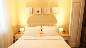 Une chambre à coucher comprenant un lit, des tables de chevet, une porte et des œuvres d’art accrochées au mur.