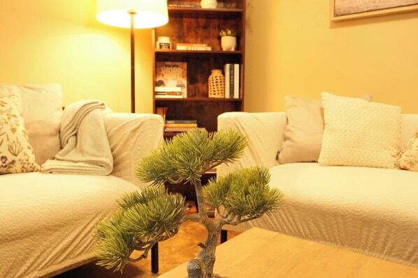 Een gezellige woonkamer met twee banken, een bijzettafeltje en een bonsaiboom.