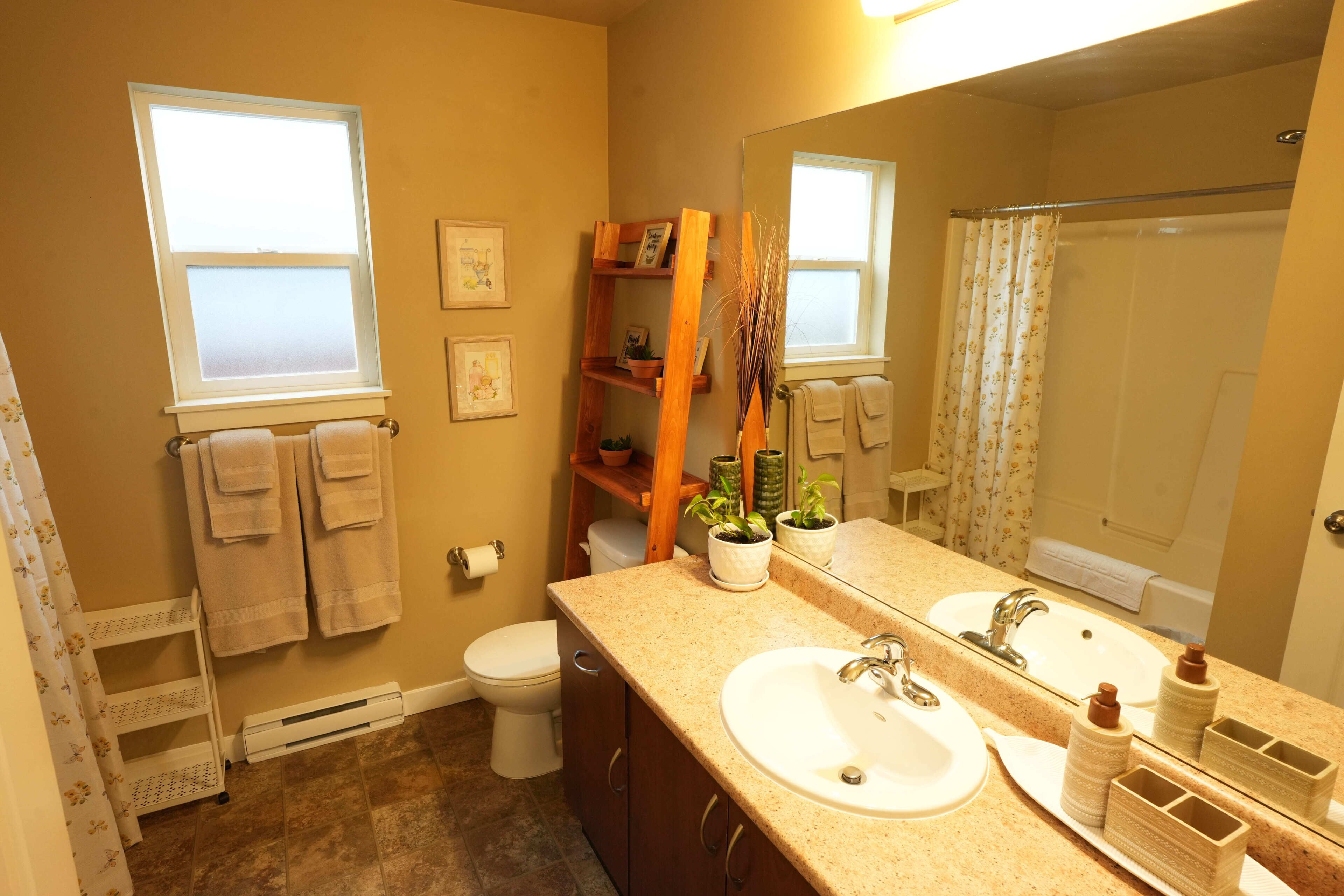 Une salle de bain avec deux lavabos, des toilettes, une douche et une fenêtre.