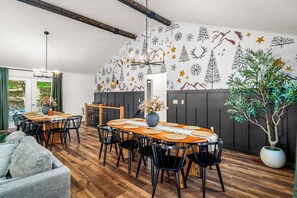 Un comedor con una mesa de madera, sillas negras y un jarrón con flores.