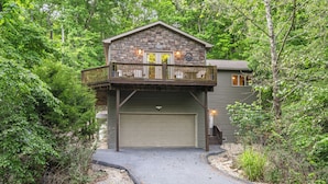 A two-story cabin with a stone facade, a balcony, and a garage.