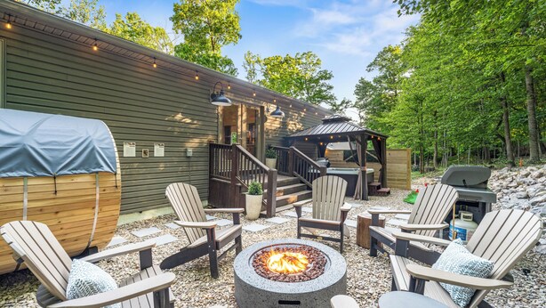 A covered outdoor seating area with Adirondack chairs and a fire pit.