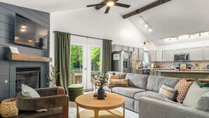 A modern living room with a fireplace, a sofa, a coffee table, and a kitchen area with cabinets and appliances.
