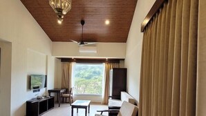 A spacious living area with a ceiling fan, a television, a sofa, and a dining table. - Mastiff Grand La Villae Resort, Lonavala (Mawal)
