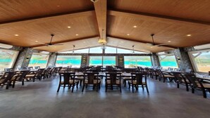 A spacious indoor area with high ceilings, wooden beams, and large windows offering a view of the outdoors. - Mastiff Grand La Villae Resort, Lonavala (Mawal)