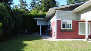 A modern house with a red exterior, a covered porch, and a well-maintained lawn.