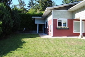 Une maison moderne à l’extérieur rouge, dotée d’un porche abrité et d’une pelouse bien entretenue.