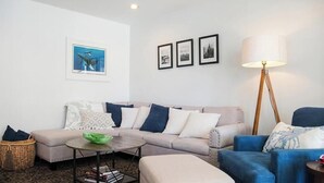 A living room with a sofa, armchairs, a coffee table, a lamp, and wall art.