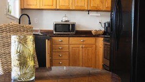 A kitchen with wooden cabinets, a black refrigerator, a microwave, and a round dining table with a glass vase.