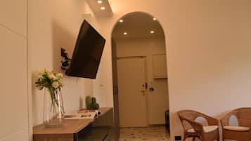 Ein modernes Interieur mit einem wandmontierten Flachbildfernseher, einem Holztischchen mit Blumenvase und Korbstühlen.