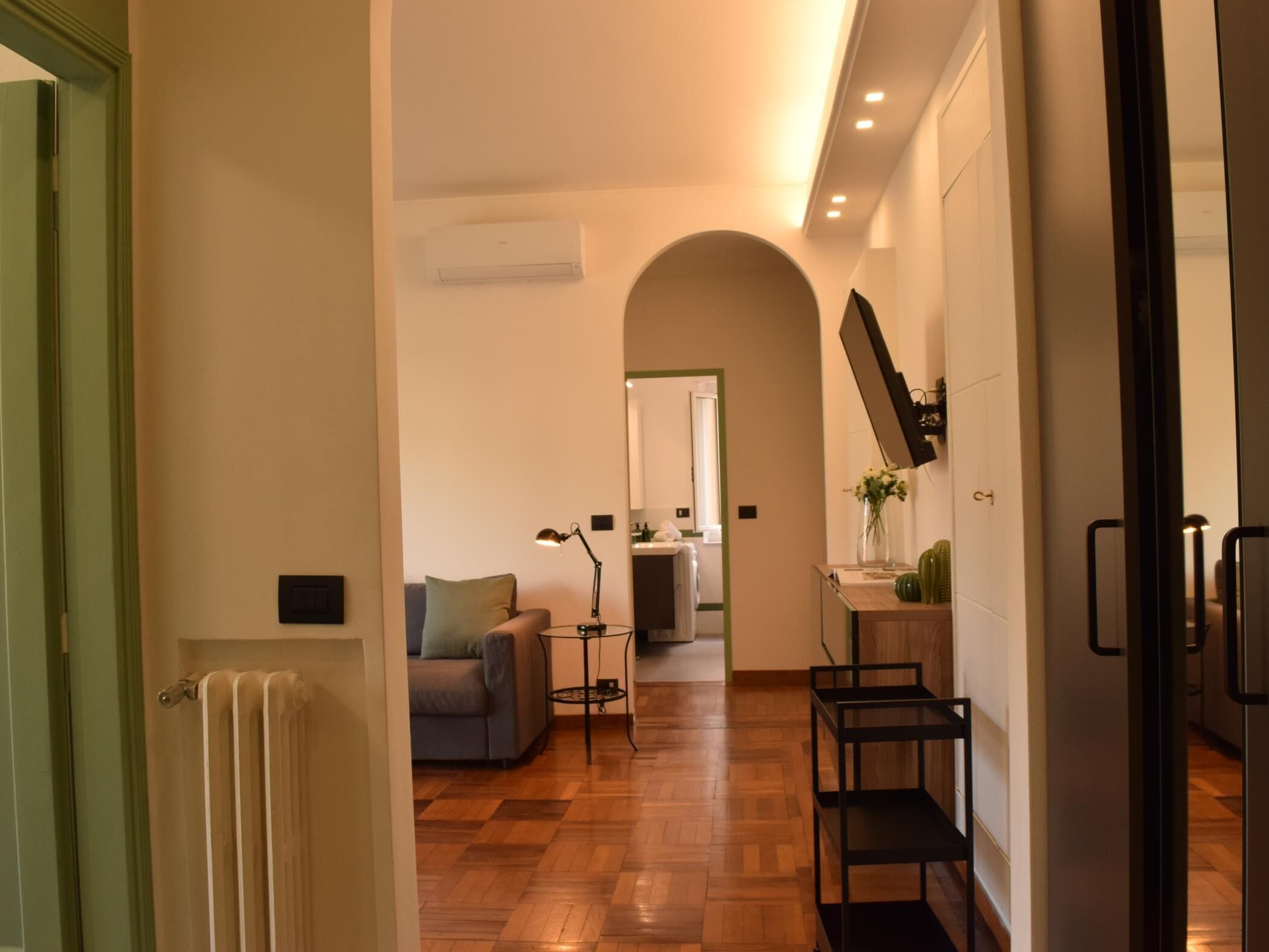 Ein Flur mit Heizkörper, Sofa, Lampe und einem Spiegel an der Wand.