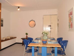 Ein Essbereich mit Holztisch, blauen Stühlen, einem runden Spiegel und einer Tür mit Lichtschalter.