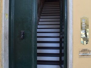 Eine Treppe führt zu einem Wohngebäude mit einer grünen Tür und einem Metall-Sprechanlage.