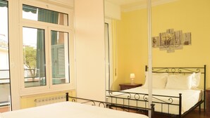 Ein Schlafzimmer mit einem Bett, einem Nachttisch, einem Spiegel und einem Fenster mit Rollläden.