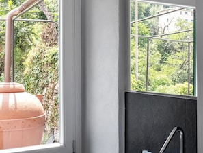 Ein Badezimmer mit großem Fenster, Duschbereich und Blick ins Grüne.