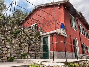 Ein rotes Gebäude mit Steinstufen und grünen Fensterläden, eingerüstet.