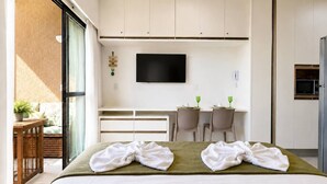 Una habitación de hotel con cama, escritorio, televisión y balcón.