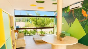 Una habitación con un ventanal grande, una mesa redonda, un sofá y un colorido mural en la pared.