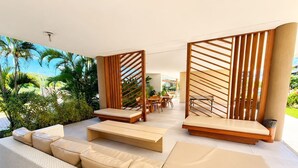 Un espacio exterior moderno con sala, sillones reclinables y un separador de madera.