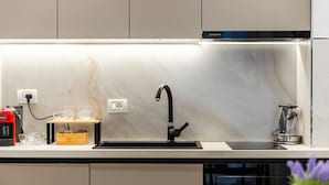 A modern kitchen with a built-in sink, a coffee machine, and a glass carafe. - Stone City Stay Central Gjirokast r Apartment (Gjirokastër)