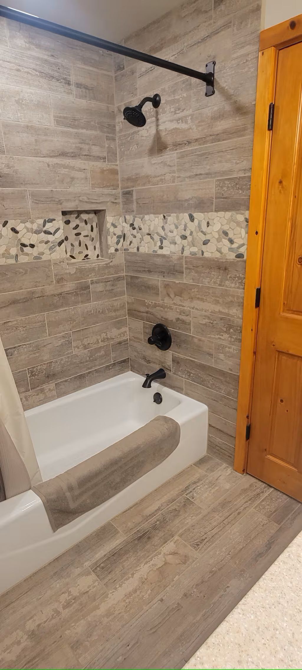A bathroom with a bathtub, shower, and wooden floor.