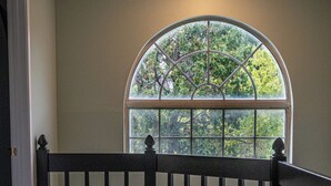 A room with a curved window, a wooden railing, and a carpeted floor. - Quiet Neighborhood walking by eagle creek close to downtown and speedway (Indianapolis)