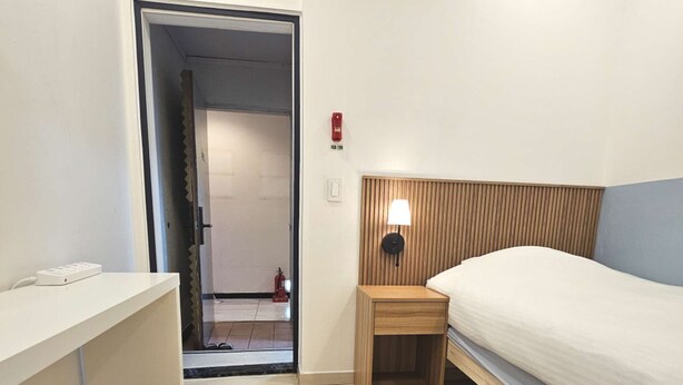 Ein Hotelzimmer mit Bett, Nachttisch, Schreibtisch und Stuhl.