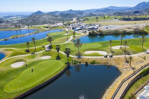 A golf course with multiple ponds, palm trees, and a mountainous backdrop. - Penthouse of Aguilon (Pulpi)