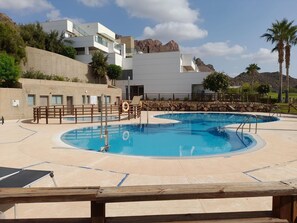 A pool area with two circular pools, a wooden deck, and a mountain backdrop. - Penthouse of Aguilon (Pulpi)