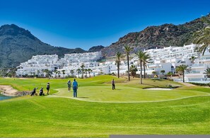 A golf course with white buildings and palm trees in the background. - Penthouse of Aguilon (Pulpi)
