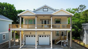 Ein zweistöckiges Haus mit einer überdachten Veranda, einer Garage und einer Treppe, die zum zweiten Stock führt.