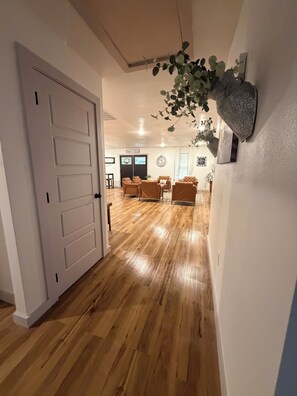 A spacious living area with wooden flooring, a large white door, and a seating arrangement.