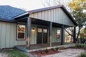 A single-story house with a covered porch, a front door, and windows.