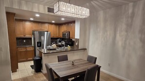 Una cocina moderna con armarios de madera, electrodomésticos de acero inoxidable y una zona de comedor con mesa y sillas de madera.