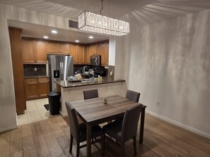 Eine moderne Küche mit Holzausstattung, Edelstahlgeräten und einem Essbereich mit Holztisch und Stühlen.