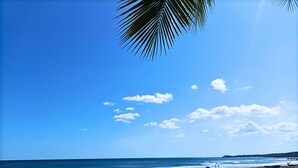Ein Strand mit blauem Himmel, ruhiger See und vereinzelten Felsen.