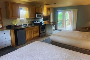 Una habitación de hotel compacta con kitchenette, una cama y vistas al exterior.
