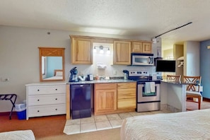 A compact kitchenette with a microwave, stove, and a small refrigerator.