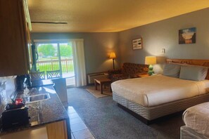 Habitación de hotel con cama, sofá, escritorio con lámpara y vistas al exterior.