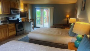 Une chambre d’hôtel avec deux lits, une kitchenette, un balcon et une télévision.