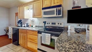 Une cuisine dotée de meubles en bois, d’un four à micro-ondes, d’un four traditionnel, d’un lave-vaisselle et d’un plan de travail en granit.