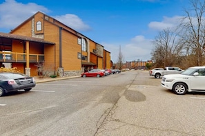 A building with a wooden facade, a balcony, and a parking lot with cars.