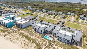 An aerial view of a coastal area with buildings, a swimming pool, and a beach. - Direct Ocean Front 3BR w/ Pool (Nags Head)