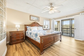 A bedroom with a wooden bed, a nightstand, a ceiling fan, and a view of the outdoors through a sliding glass door.