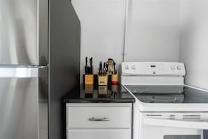 A kitchen with a stainless steel refrigerator, a white stove, and a black countertop. - 
The Colonial Art House, Spacious 5BR Historic Gem (Alexandria)