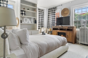 A bedroom with a bed, a TV, a fireplace, and a window with curtains. - 
The Colonial Art House, Spacious 5BR Historic Gem (Alexandria)
