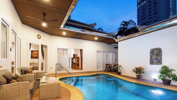 An indoor swimming pool with wicker furniture, a ceiling fan, and a clock on the wall. - Luxury 4BR Pool Villa Pratamnak Soi5 - 50m to Beach (Pattaya)