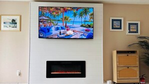 A living room with a flat-screen TV mounted above a fireplace, a sofa, and a coffee table.